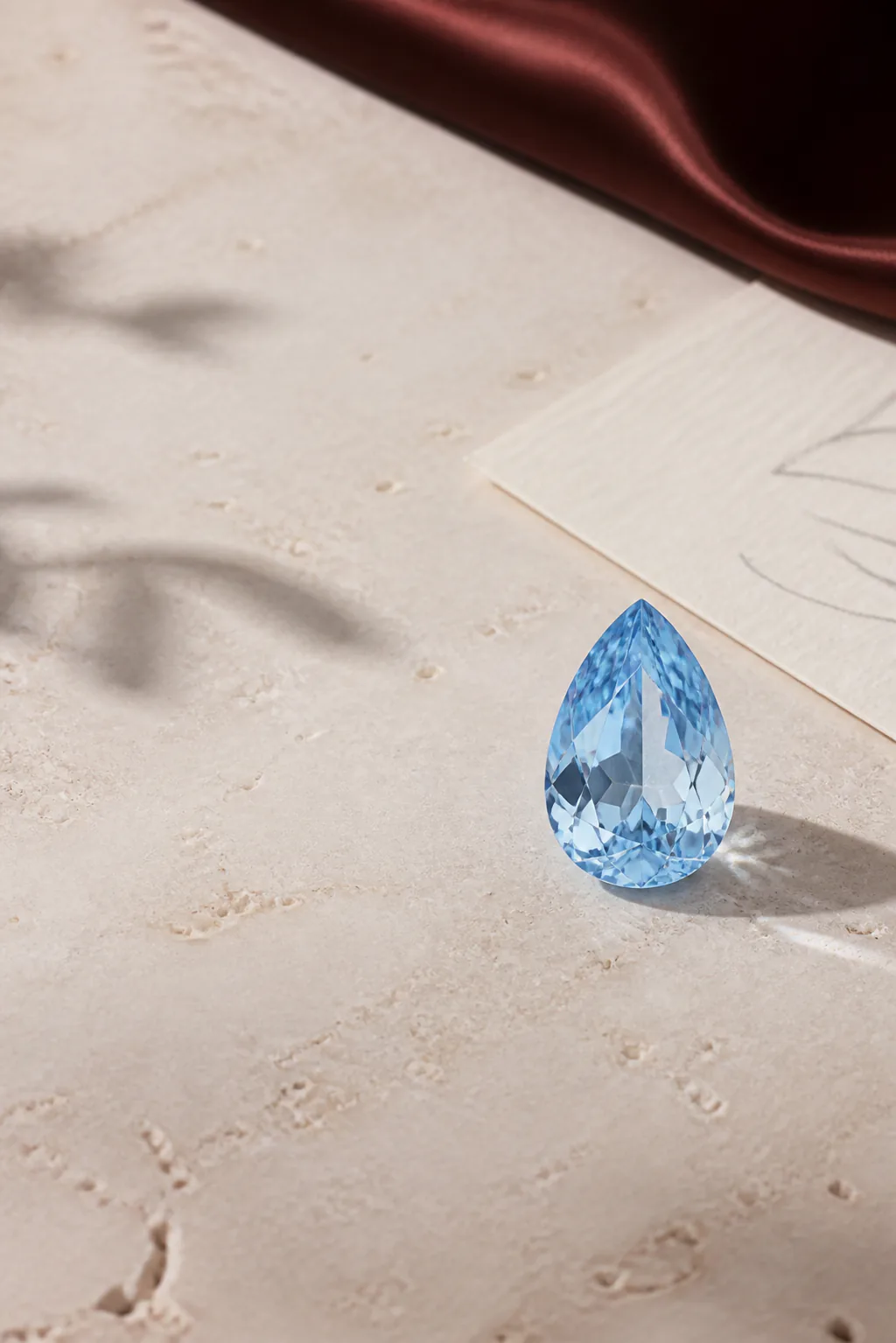 Light blue loose gemstone design direction beside a jewelry sketch.