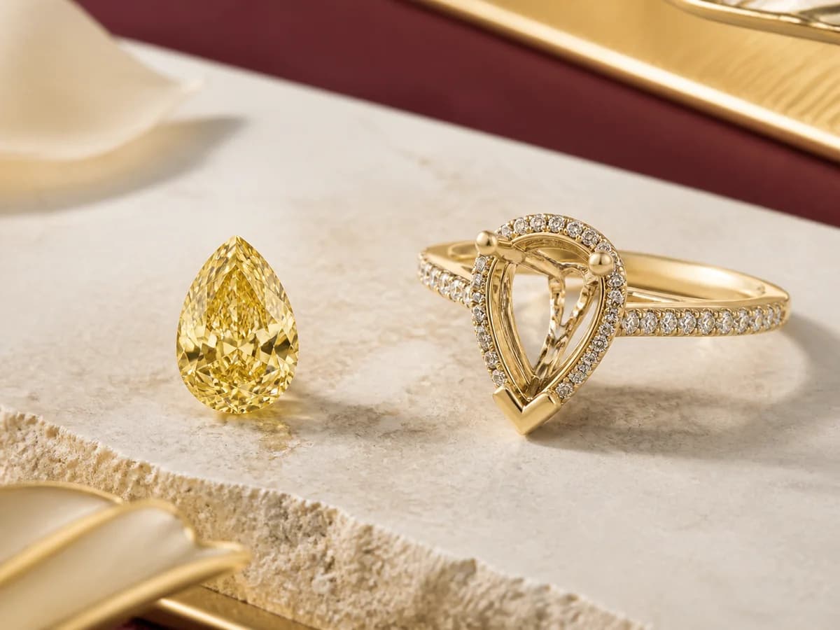Illustrative people-free jewelry still life with a yellow pear laboratory-grown diamond direction and a complementary protected-point ring setting