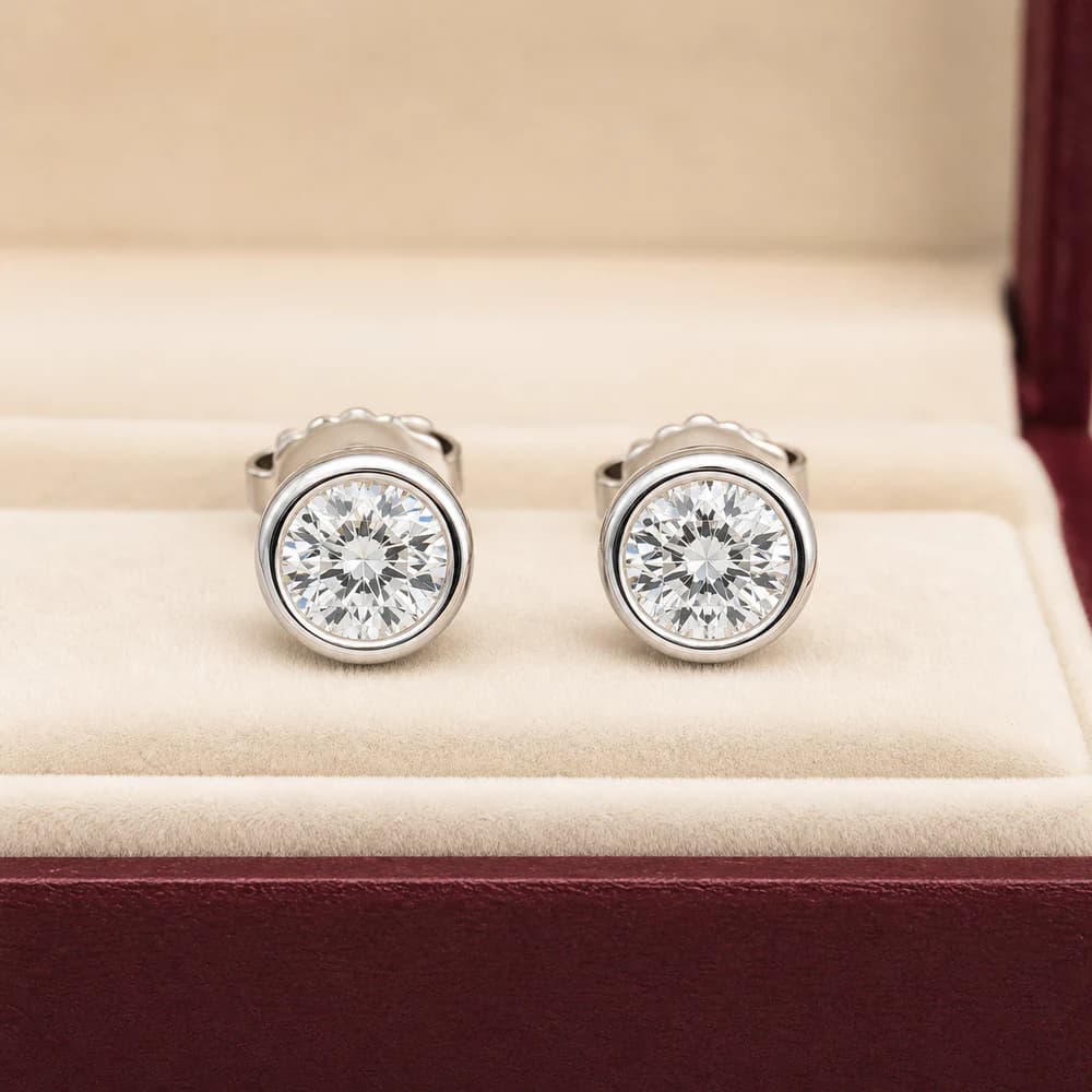 Bezel-set stud earrings shown from the front in a jewelry box
