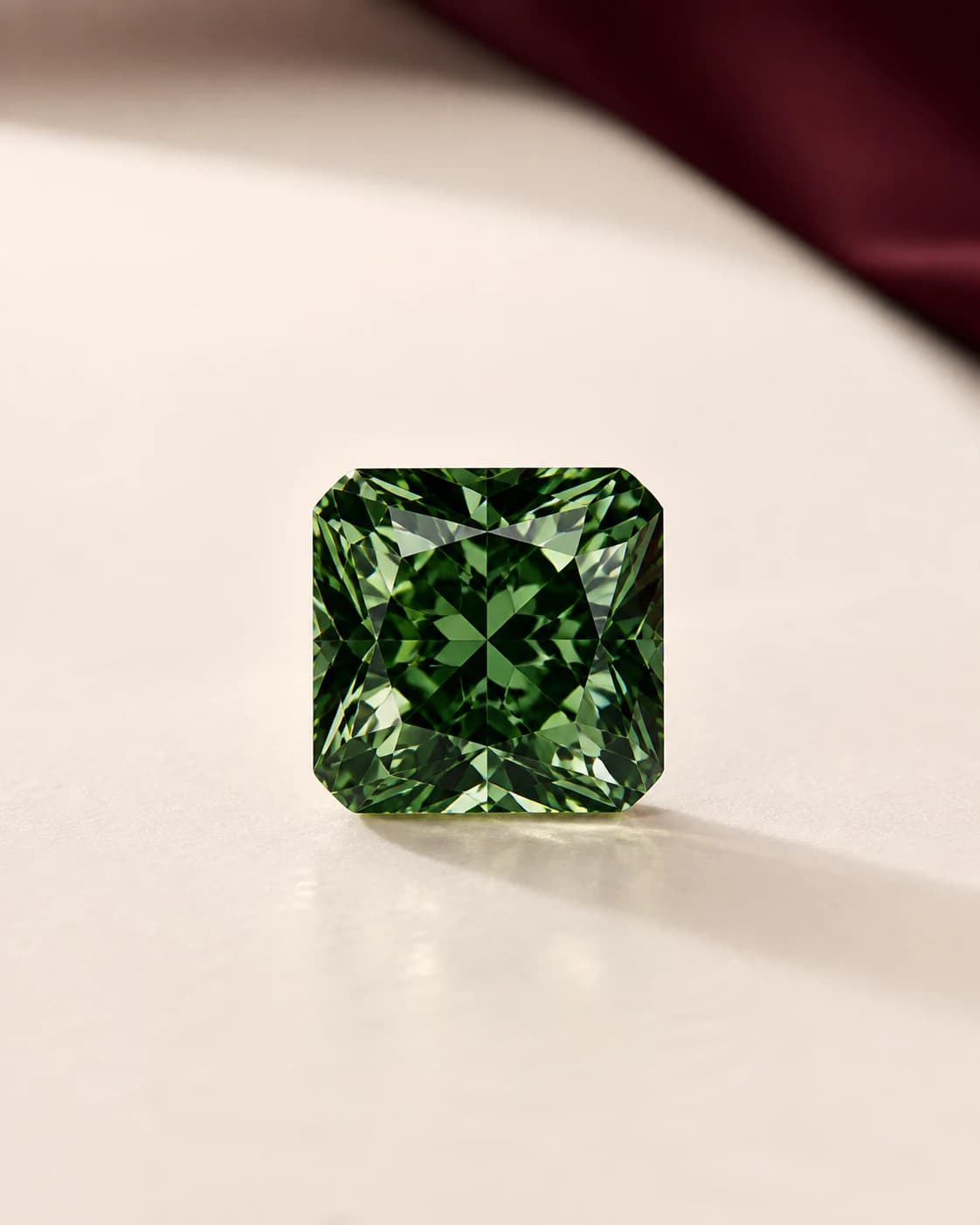 A deep green laboratory-grown diamond in warm editorial studio light.