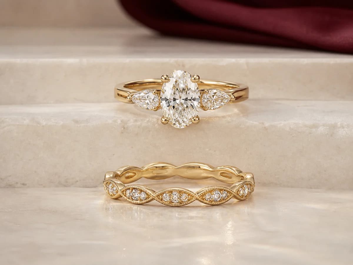 An oval three-stone engagement ring and a separate sculptural wedding band sharing a restrained marquise-leaf rhythm.